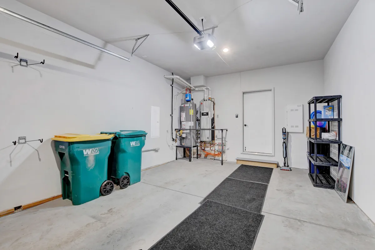 A practical interior garage scene with organized green trash bins, a water heater, and a storage shelf, demonstrating ample space for storing gear or parking. The area is clean and functional, emphasizing convenience for adventure lovers.
