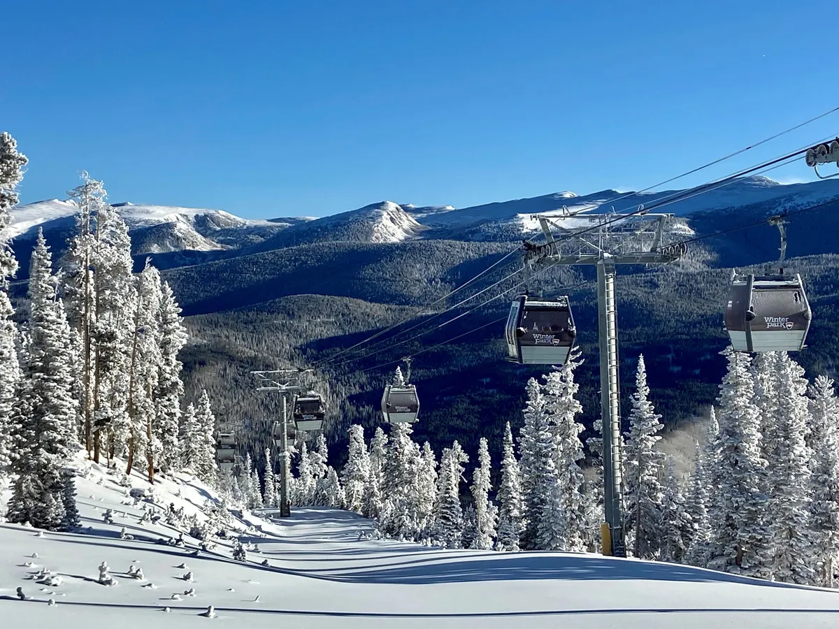 A sweeping exterior view of snow-covered trees with ski lift gondolas ascending toward a mountain backdrop. The scene is alive with the promise of winter adventure, showcasing the landscape's suitability for skiing, snowboarding, and other cold-weather activities.