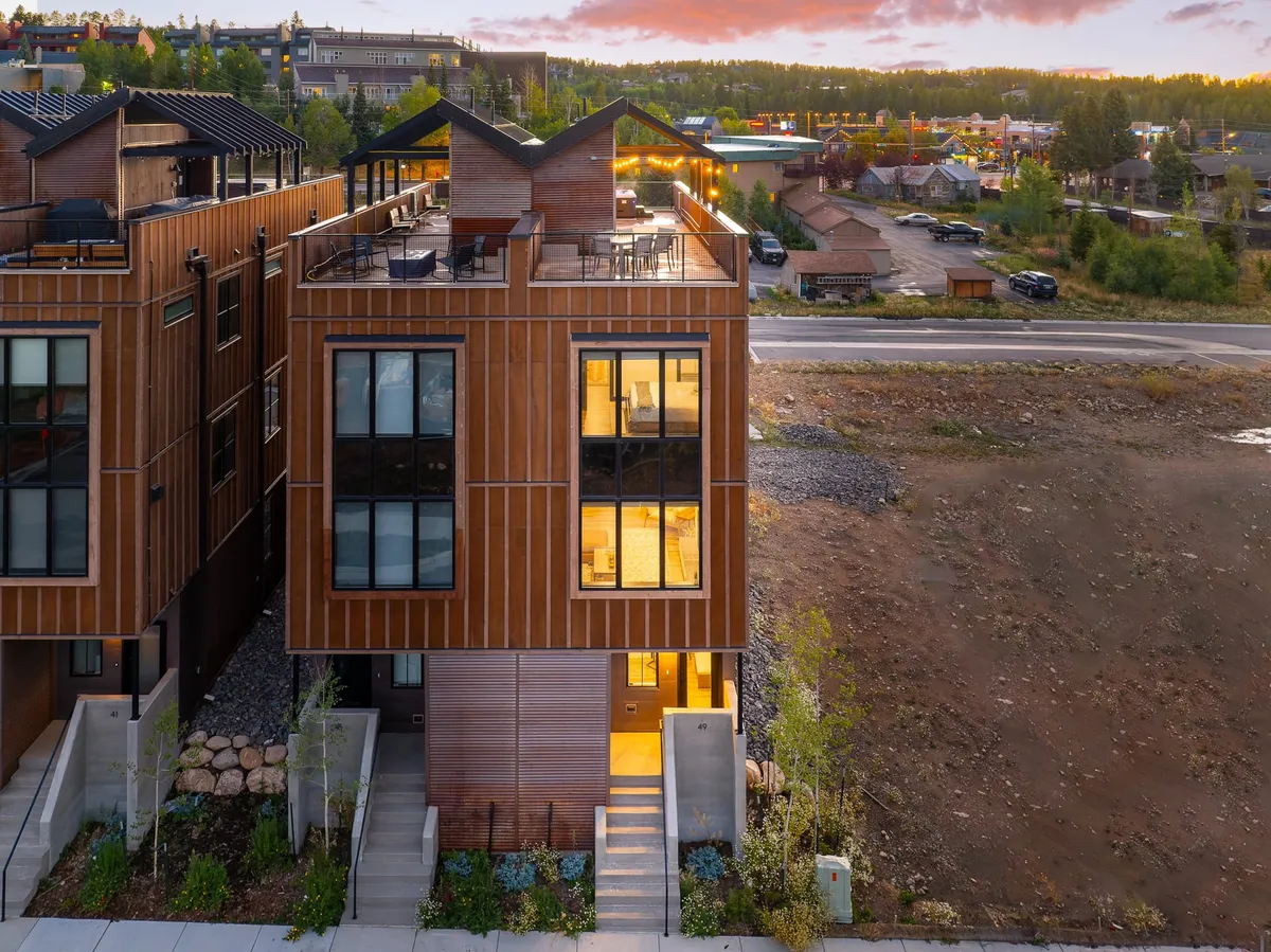 This image presents the exterior of the property, highlighting its modern architectural design, expansive windows, and a rooftop terrace ideal for gatherings or relaxation. The rooftop terrace offers sweeping views of the surrounding landscape, emphasizing the blend of luxury and immersion in nature.
